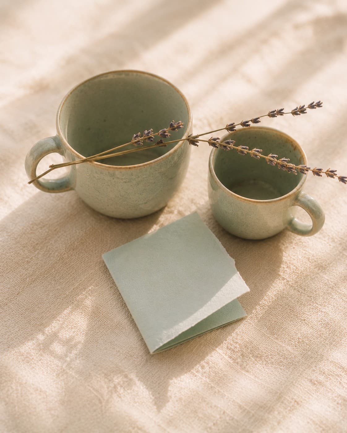 A still life of two ceramic cups and a handwritten note on a cream surface, suggesting steady support through change